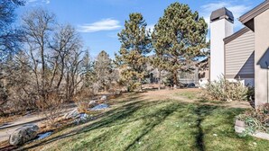 A residential property with a well-maintained lawn, a stone pathway, and a large tree in the background. - Charming Rustic Avon Mountain Condo; near lift (Avon)