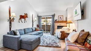 A modern living room with a sectional sofa, a fireplace, and a mounted deer head. - Charming Rustic Avon Mountain Condo; near lift (Avon)