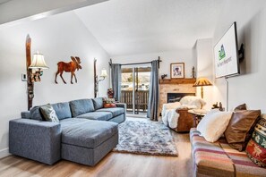 Ein modernes Wohnzimmer mit einer Eckcouch, einem Kamin und einem aufgehängten Hirschkopf.
