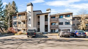 A multi-story residential building with balconies, a parking lot, and surrounding trees. - Charming Rustic Avon Mountain Condo; near lift (Avon)