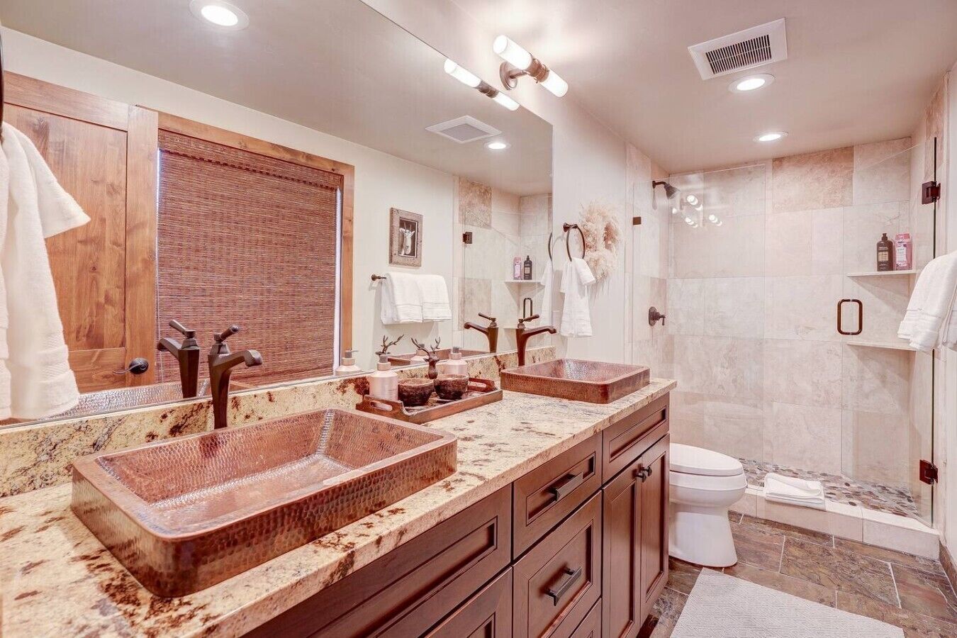Une salle de bain moderne avec un grand miroir, deux lavabos, une douche et des toilettes.