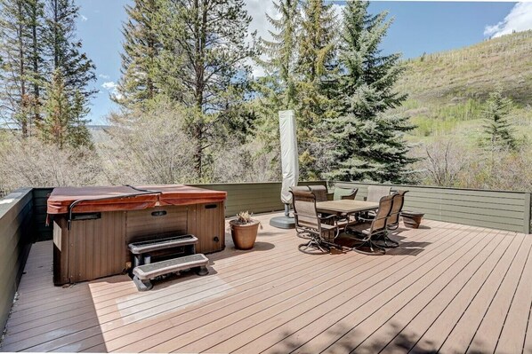 An outdoor deck with a barbecue grill, a table with chairs, and a potted plant.