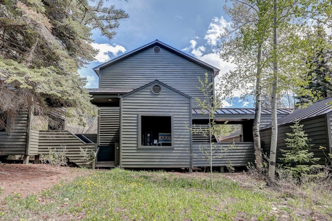 A rustic cabin with a gabled roof, a central window, and a small porch area.