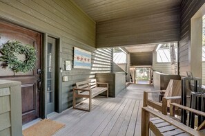 A wooden porch with a bench, a door with a wreath, and a framed picture on the wall.