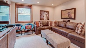A living room with a brown leather sofa, two armchairs, a coffee table, and a fireplace.