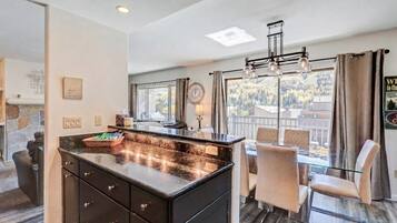 Una cocina moderna con una isla grande, comedor con sillas y vistas al exterior.