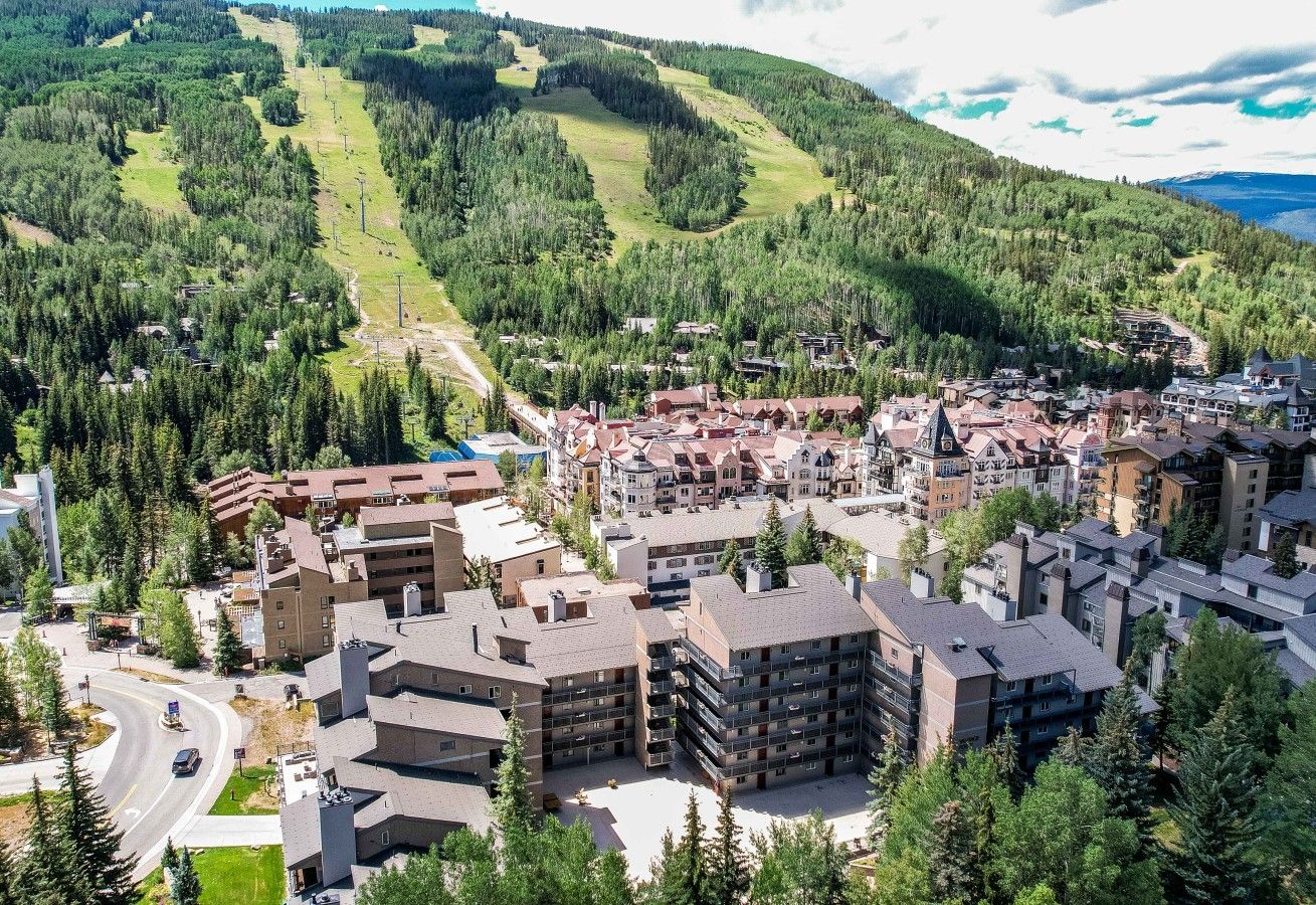 Un quartier résidentiel composé d’immeubles à plusieurs étages, de routes et bordé par des montagnes.