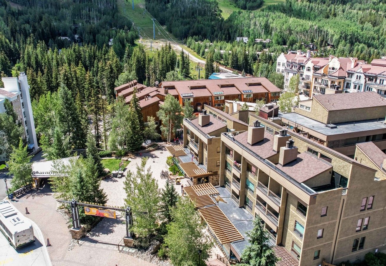 Un hotel de varios pisos con un patio central, rodeado de un bosque denso.