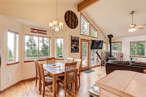 A spacious living area with a dining table, chairs, a fireplace, a television, and large windows offering views of the outdoors. - Mountain View Retreat / Game Room, Fireplace (Fairplay)