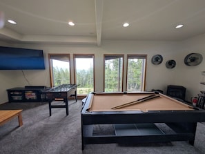 A room with a pool table, a foosball table, and a television. - Mountain View Retreat | Game Room & Fireplace (Fairplay)