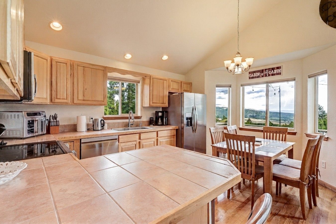 A spacious kitchen with wooden cabinets, a stainless steel refrigerator, and a large island with seating.