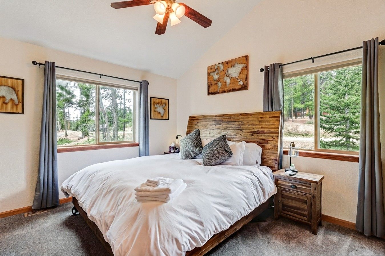 A bedroom with a large bed, a wooden headboard, a nightstand, and a ceiling fan.