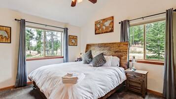 A bedroom with a large bed, a wooden headboard, a nightstand, and a ceiling fan.