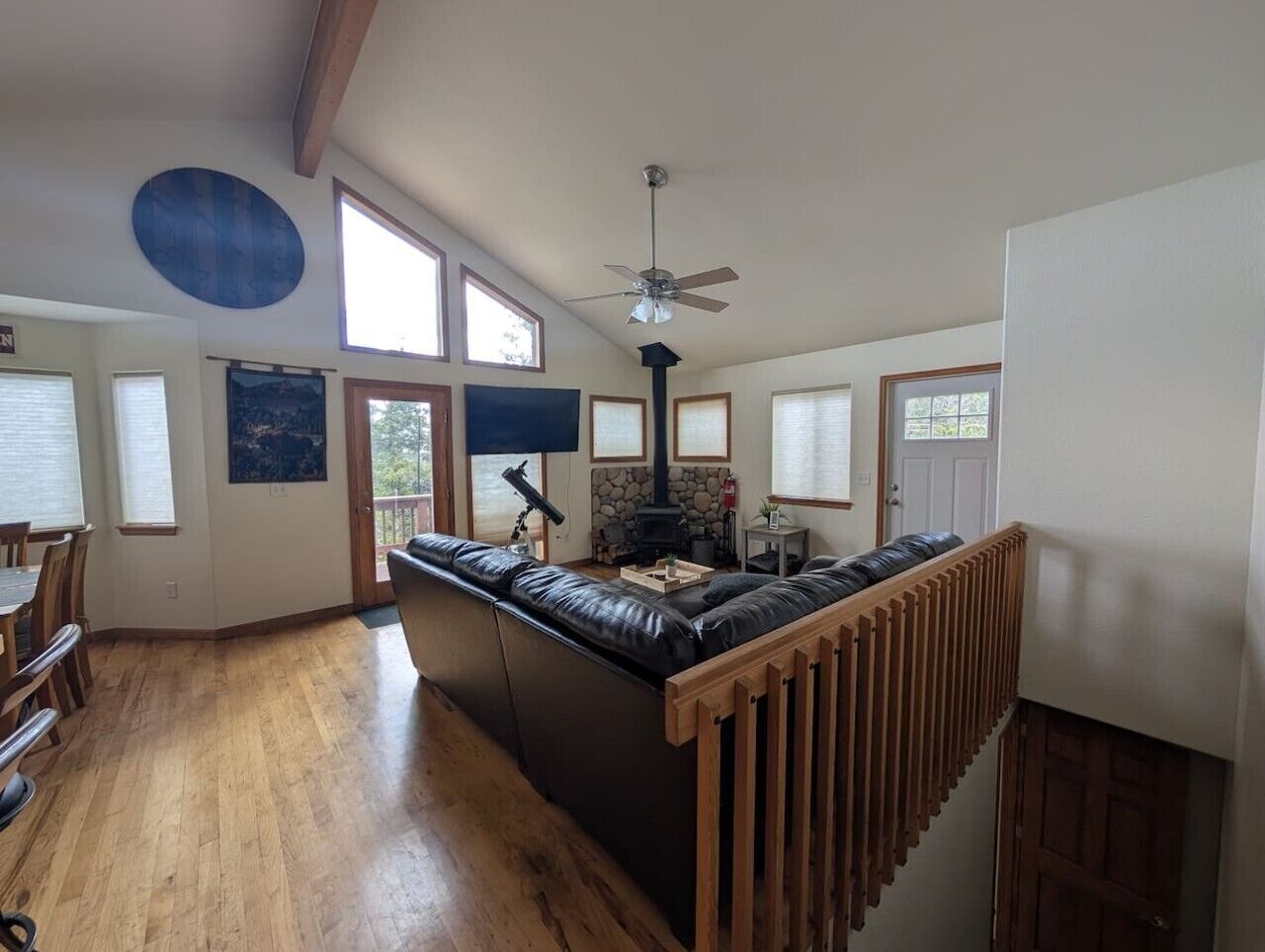 A spacious living area with a fireplace, a large window, and a high ceiling fan.
