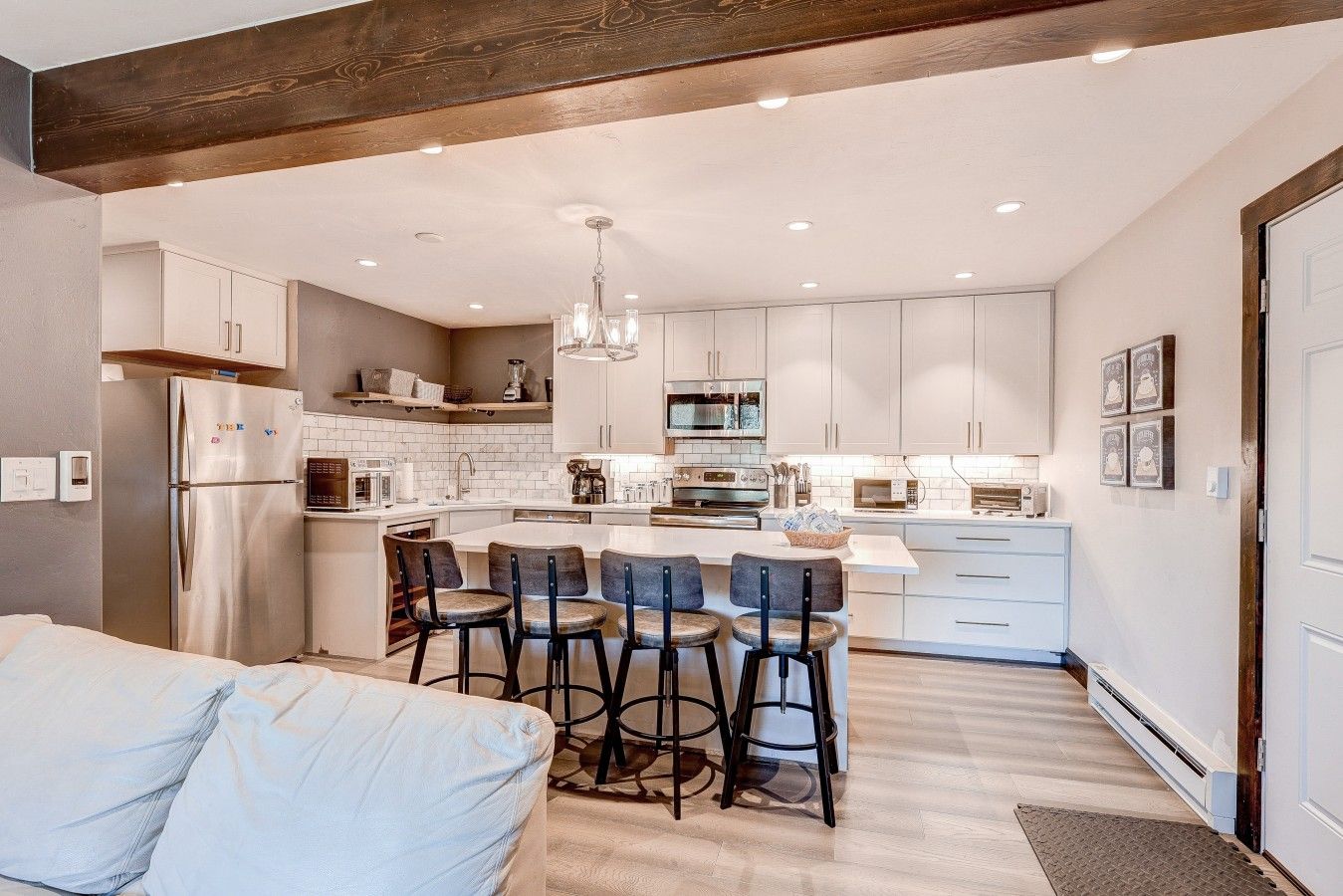 A modern kitchen with a central island, bar stools, and built-in appliances.