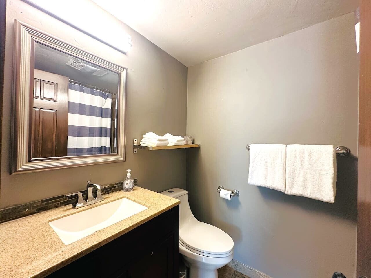Un bagno con lavandino, specchio, WC e portasciugamani.