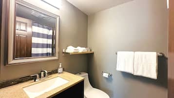 Un bagno con lavandino, specchio, WC e portasciugamani.