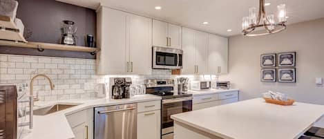 A modern kitchen with stainless steel appliances, white cabinetry, and a central island.