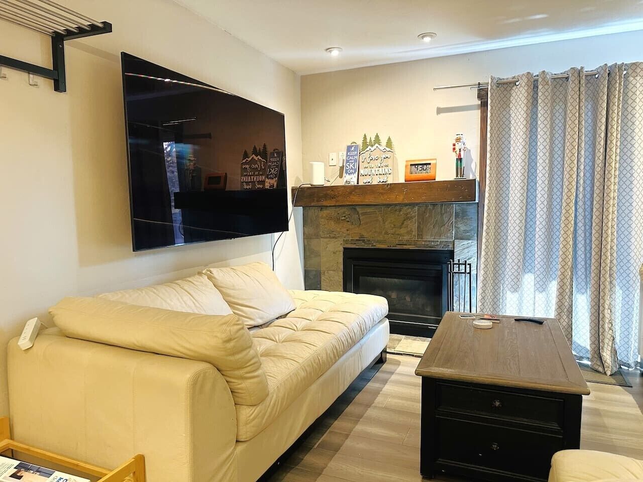 Un salon comprenant un canapé, un téléviseur à écran plat fixé au mur, une cheminée et une table basse.