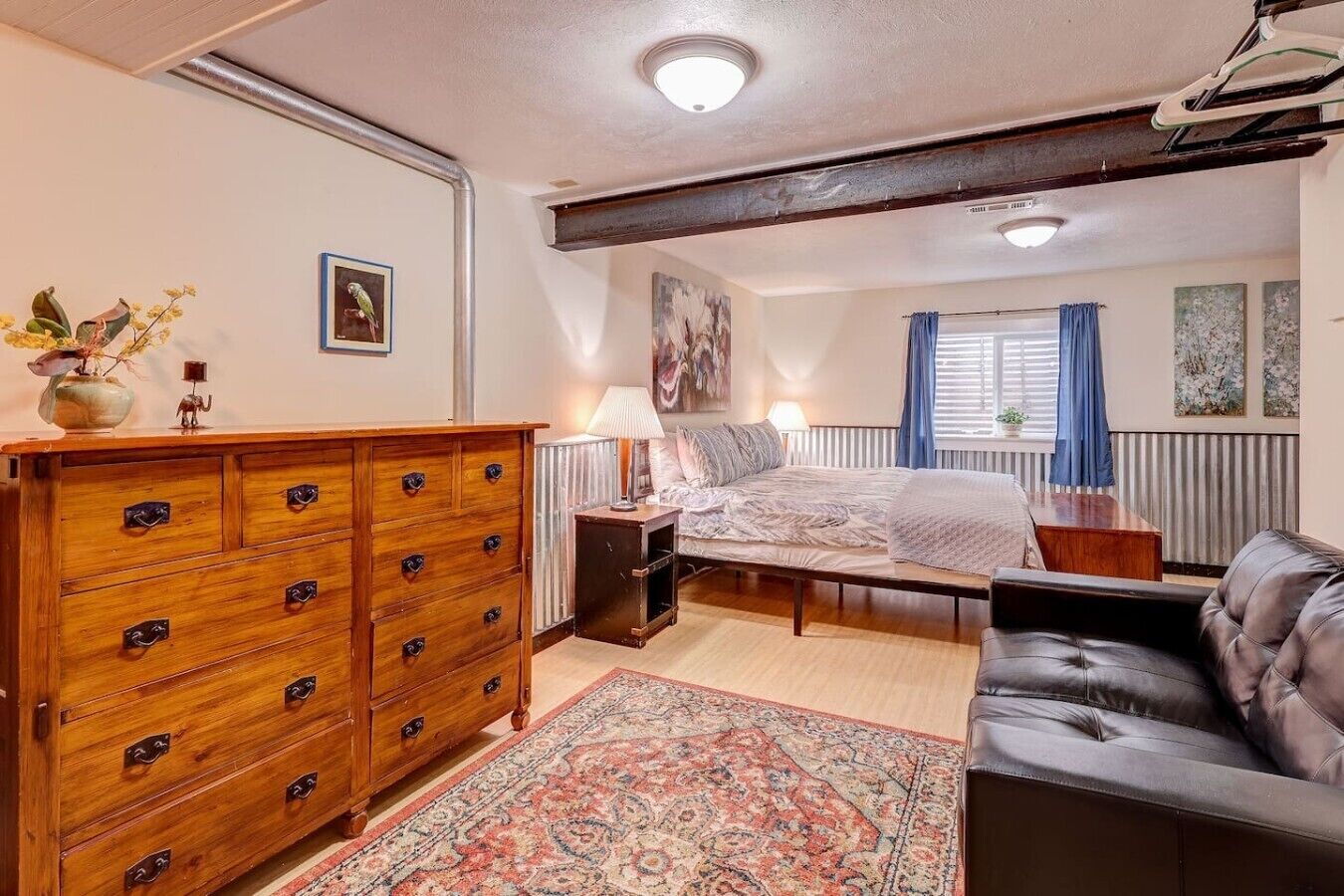 Une chambre à coucher comprenant un lit, une commode, un canapé, un tapis et un radiateur.