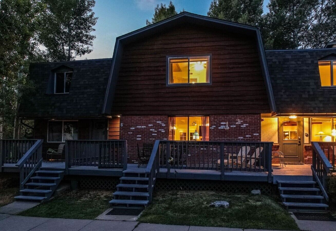 A two-story building with a wooden exterior, a front porch with steps, and a visible door.