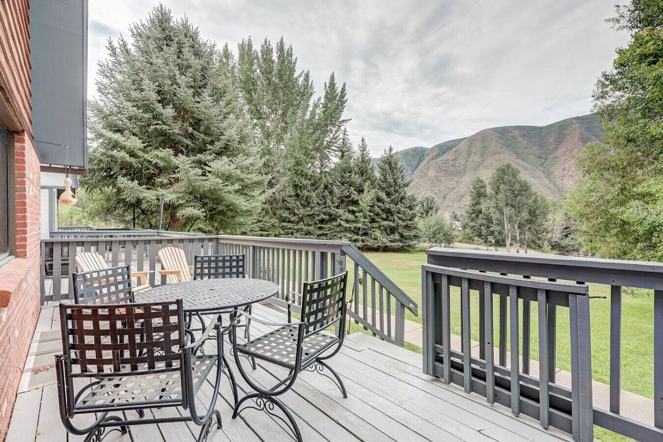 Une terrasse avec une table et des chaises, entourée d’arbres et offrant une vue sur les collines.