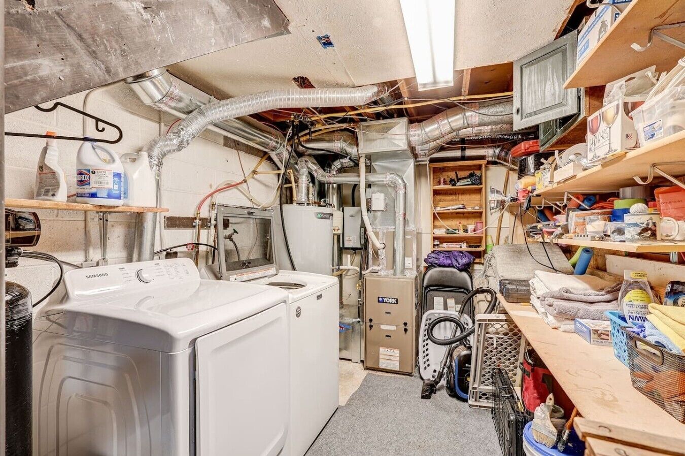 Une petite buanderie équipée d’un lave-linge, d’un sèche-linge et d’un petit aspirateur.