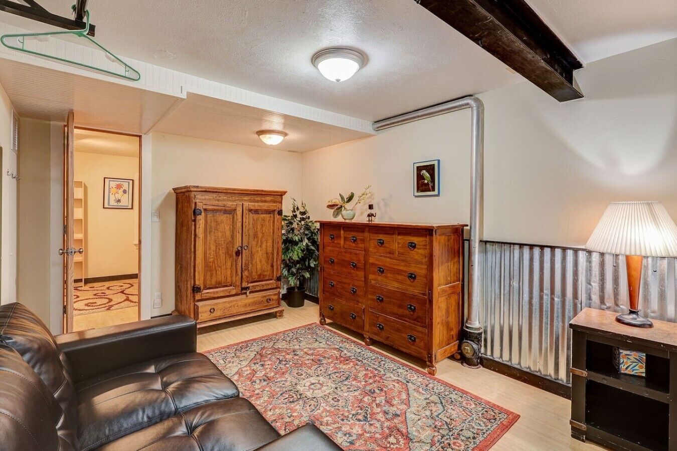 Un salon avec un canapé en cuir, des meubles en bois, un tapis à motifs et un radiateur.