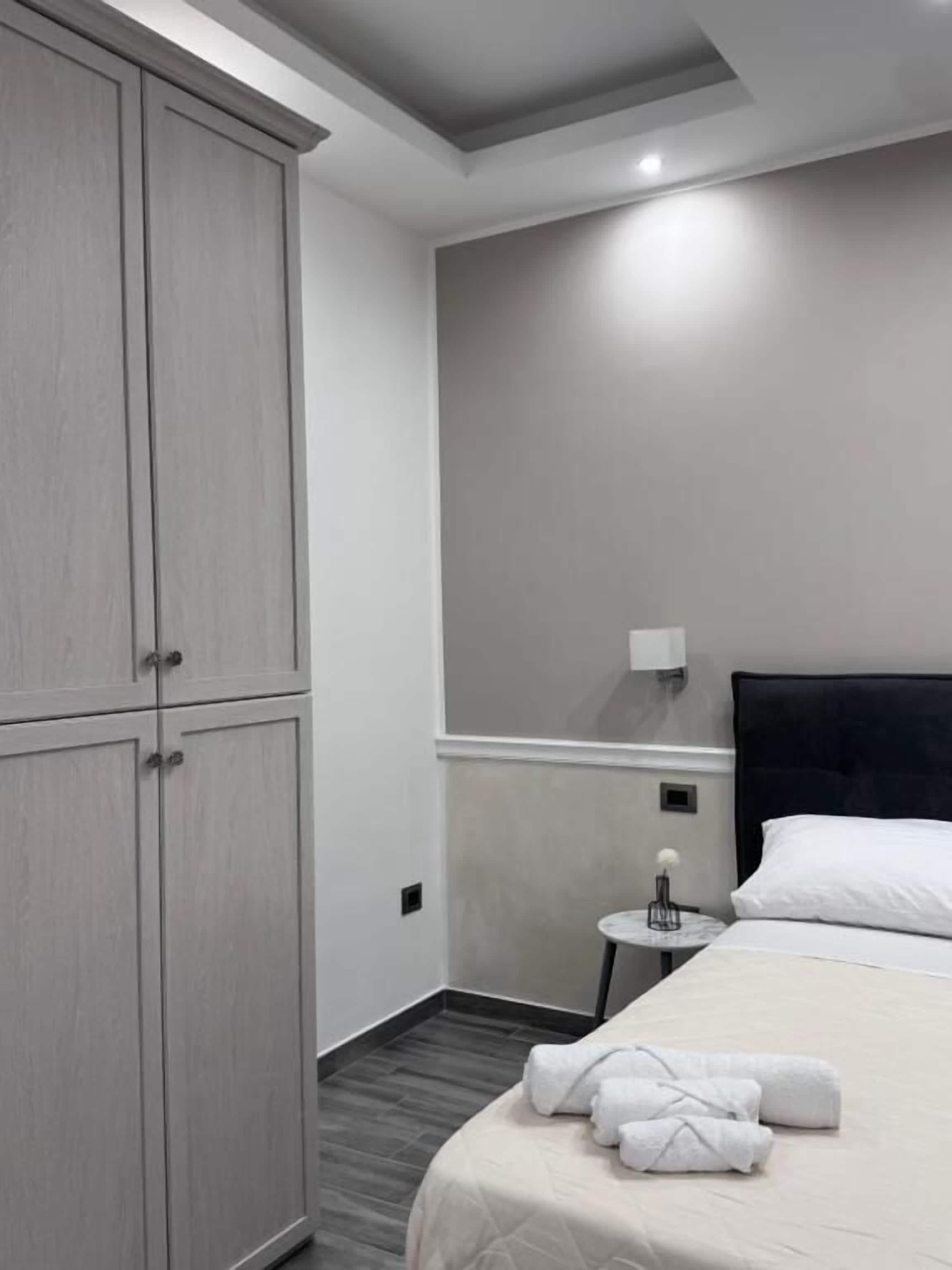 Une chambre d’hôtel comprenant un lit, une table de chevet, une lampe et une armoire.