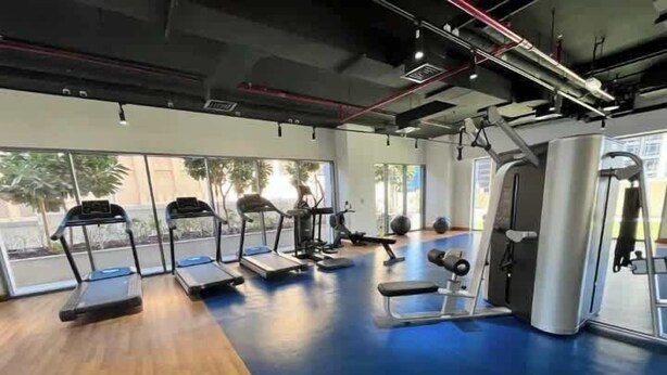 A gym with treadmills, weight machines, and a blue floor. - Burj Views Studio - Downtown Dubai -Bills Included (Dubai)