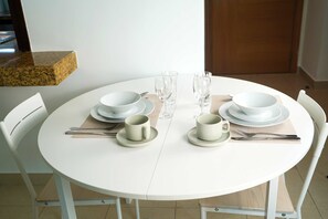 A round dining table set with plates, bowls, glasses, and cutlery. - Burj Views Studio - Downtown Dubai -Bills Included (Dubai)