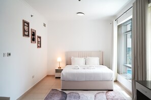 A modern bedroom with a large bed, bedside lamps, and a view of the outdoors. - Burj Views Studio - Downtown Dubai -Bills Included (Dubai)