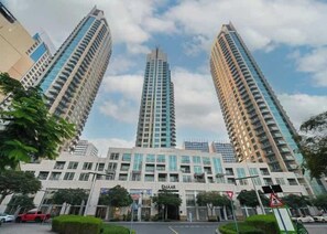 A high-rise building with multiple floors, a central entrance, and surrounding greenery. - Burj Views Studio - Downtown Dubai -Bills Included (Dubai)