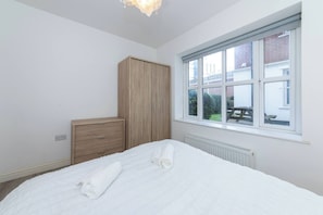 A bedroom with a bed, a wooden wardrobe, a window, and a radiator. - IBEX HOUSE Free parking 2Bed Fully equipped Flat (Reading)