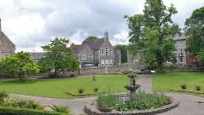 Historiallinen rakennus, jossa on kirkontorni, suihkulähde ja hyvin hoidetut puutarhat.