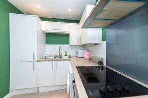 A compact kitchen with white cabinets, a black stove, and a microwave. - IBEX HOUSE Free parking 2Bed Fully equipped Flat (Reading)