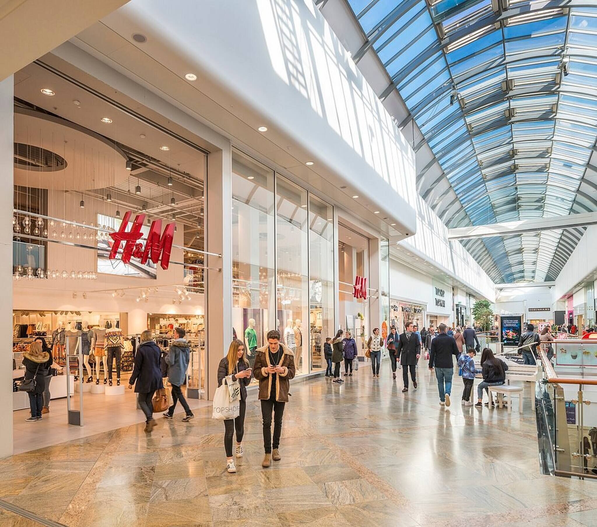 En butiksgalleria med högt i tak och glaspartier, där man hittar butiker som H&M och Topshop.