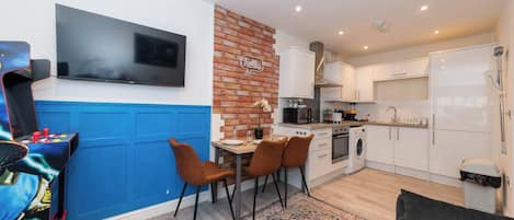 A compact living space with a dining area, kitchen, and a television mounted on the wall.