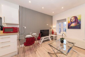 A modern living room with a houndstooth-patterned wall, a red microwave, a glass coffee table, and a painting of a famous artwork. - IBEX HOUSE Modern 2-Bed Flat Free Parking (Reading)