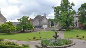 Un bâtiment historique doté d’un clocher d’église, d’une fontaine et de jardins bien entretenus.