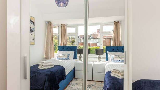 Une chambre avec deux lits, une grande fenêtre et une vue sur l’extérieur.