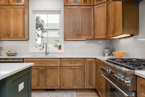 Une cuisine avec des armoires en bois, une cuisinière en acier inoxydable et une fenêtre.
