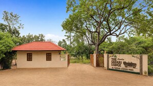 L’entrée d’un lodge de safari, avec un bâtiment en briques et un toit recouvert de tuiles rouges.
