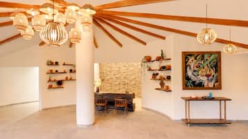 Una habitación amplia con pared de piedra, vigas de madera y un comedor con sillas y mesa.