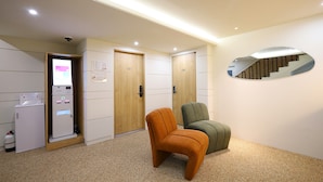 A hotel lobby with a reception area, a security camera, a vending machine, and two chairs.