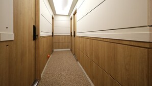 A narrow hallway with wooden walls and a carpeted floor, leading to a door at the end.