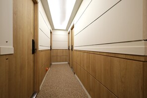 Un pasillo estrecho con paredes de madera y piso alfombrado, que conduce a una puerta al final.