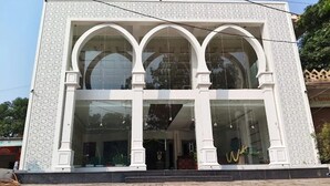 A building with a symmetrical facade, large glass windows, and a central entrance with a decorative arch. - Hotel Narayana Palace (Khajuraho)