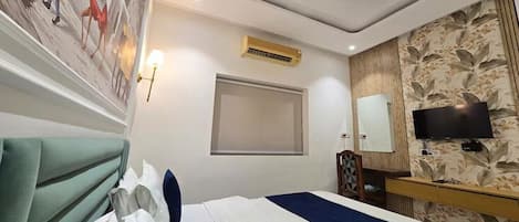 Habitación de hotel con cama, televisión, aire acondicionado de pared y ventana.