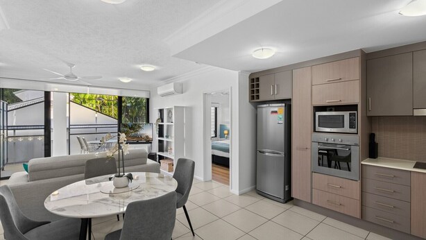 Uma cozinha moderna com eletrodomésticos embutidos, uma sala de jantar com mesa de mármore e vista para o exterior.